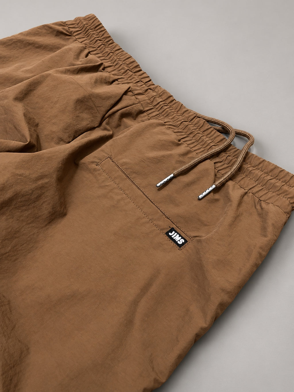 Close-up tan pants waistband, side pocket and logo tag